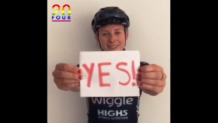 Cyclist Annette Edmondson holds a sign saying the word Yes.