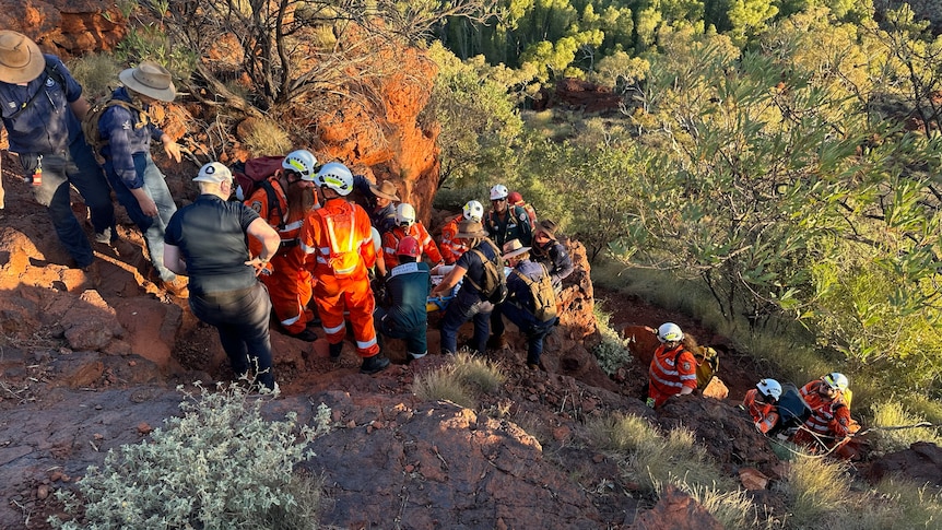 A crew of SES volunteers carrying an injured woman out of a gorge.