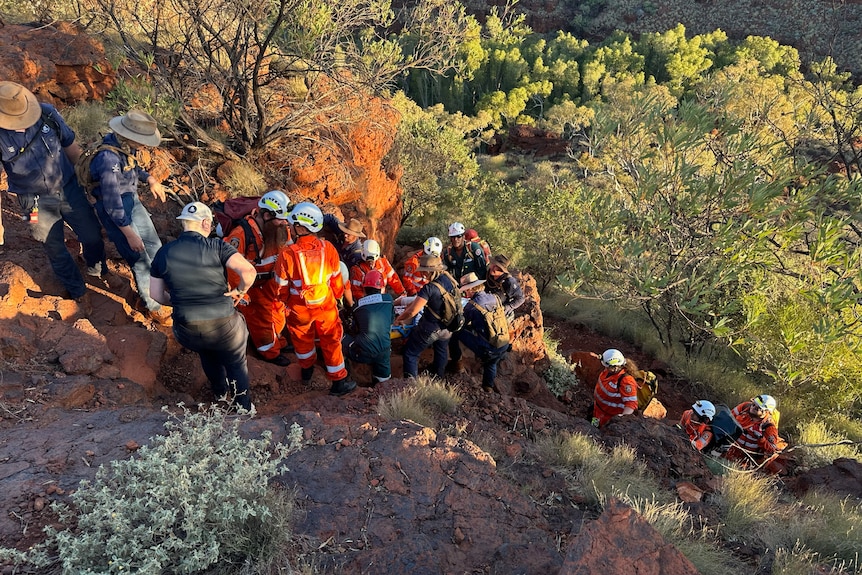A crew of SES volunteers carrying an injured woman out of a gorge.
