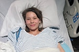 A young woman lying in a hospital bed.