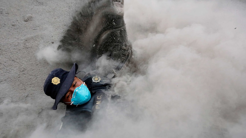 A police officer more than half engulfed in smoke.