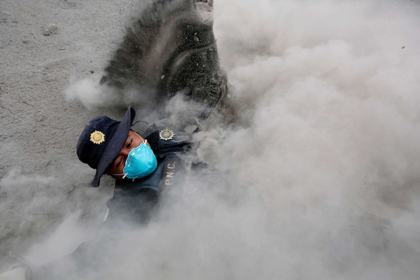 A police officer more than half engulfed in smoke.