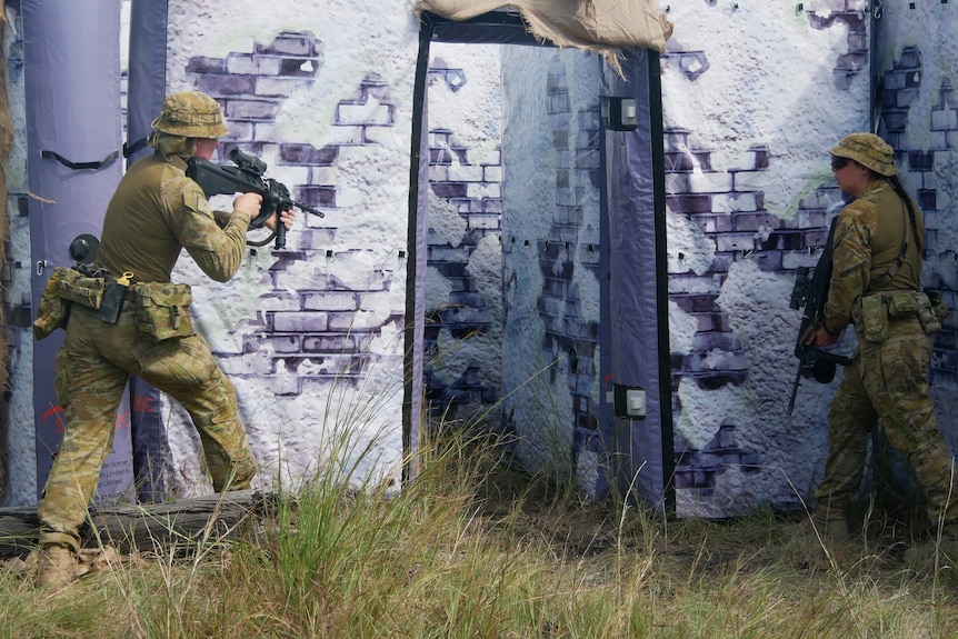 Two soldiers stand either side and inflatable structure's door with guns