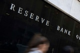 Two people walk past the Reserve Bank of Australia building in Sydney