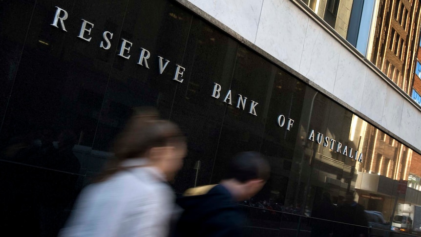 Two people walk past the Reserve Bank of Australia building in Sydney