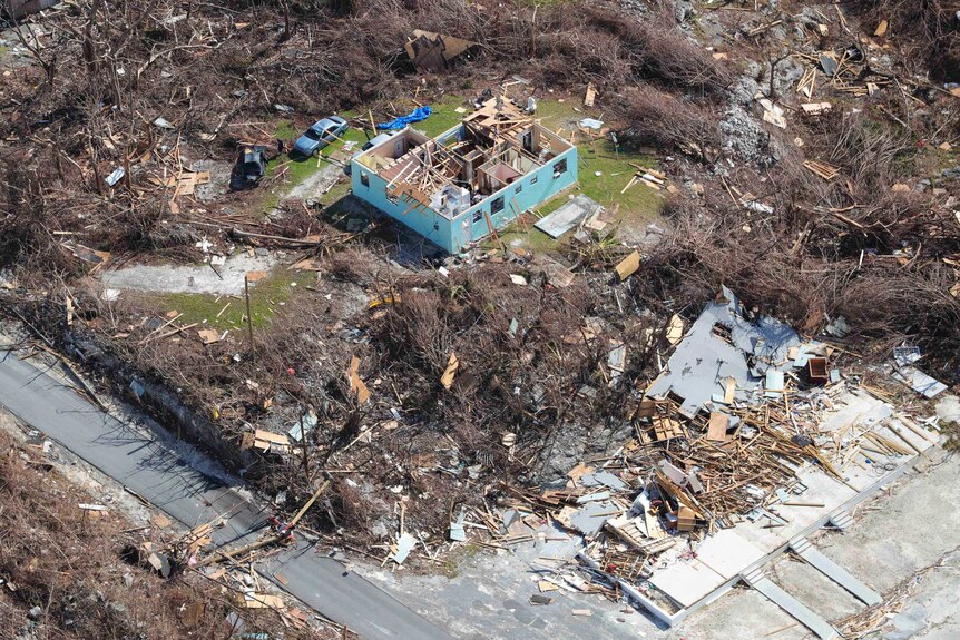 A view from above of a blue house with no roof and rubble scattered everywhere
