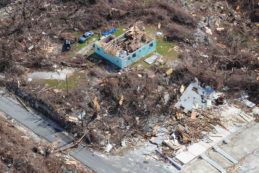 A view from above of a blue house with no roof and rubble scattered everywhere