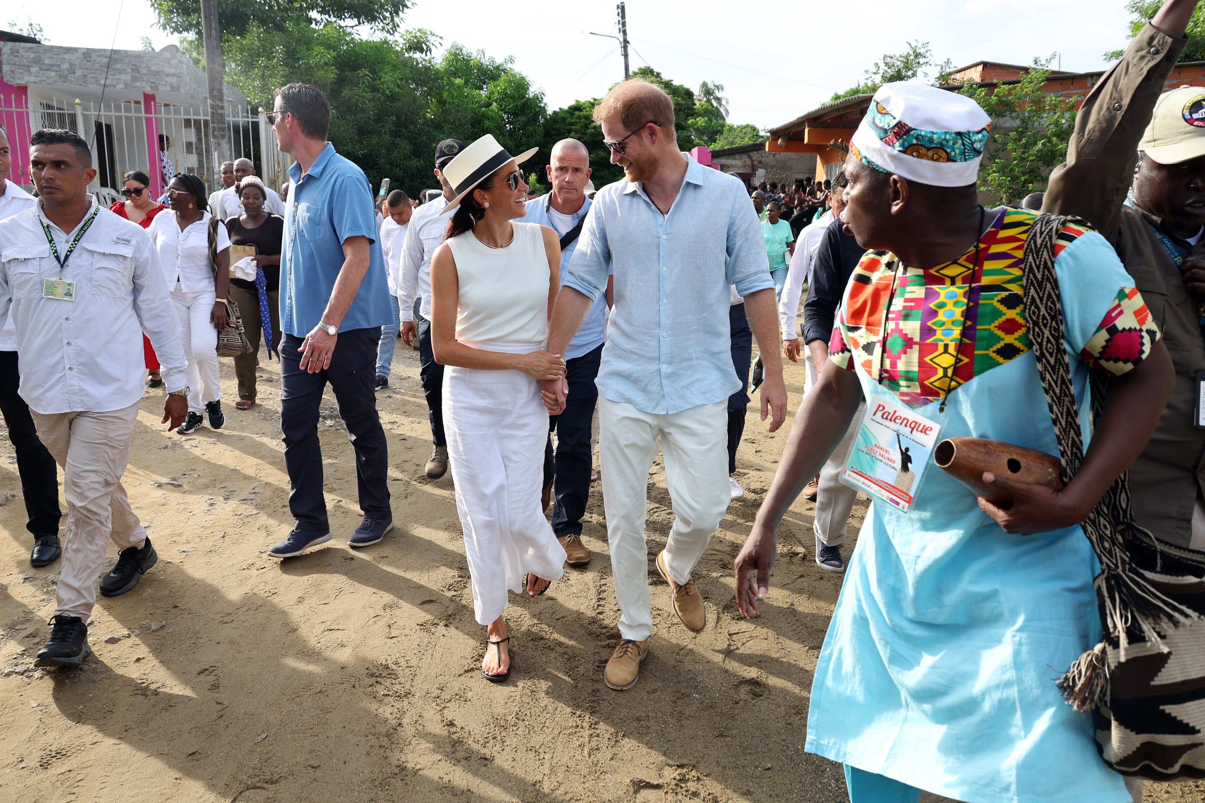 Harry and Meghan smiling and walking down the streets, surrounded by people.