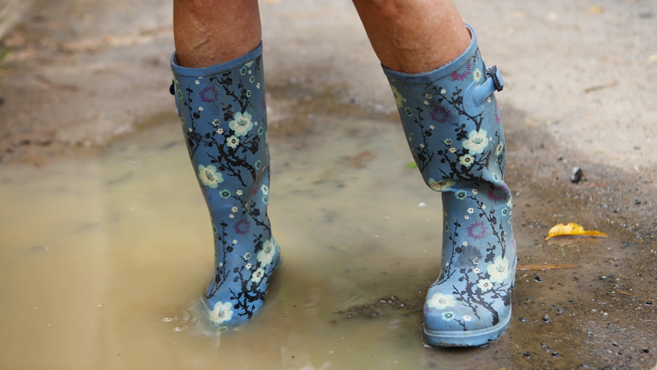 Blue, flowery gumboots in the mud.