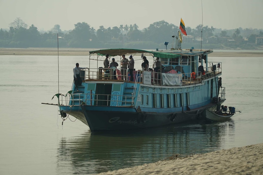 A big blue boat decorated with dolphins carries passengers down the river