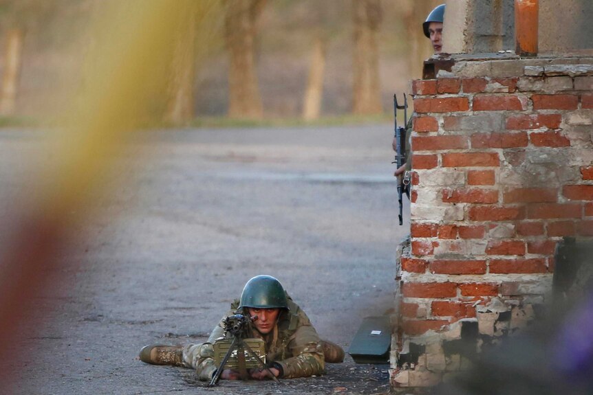 A Ukrainian soldier aims his weapon at pro-Russia protesters  in front of a Ukrainian airbase.