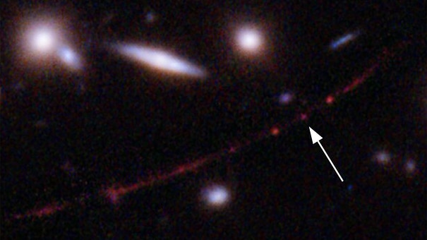 A slightly blurry image of a small group of distant stars, with an arrow pointing to one of them.