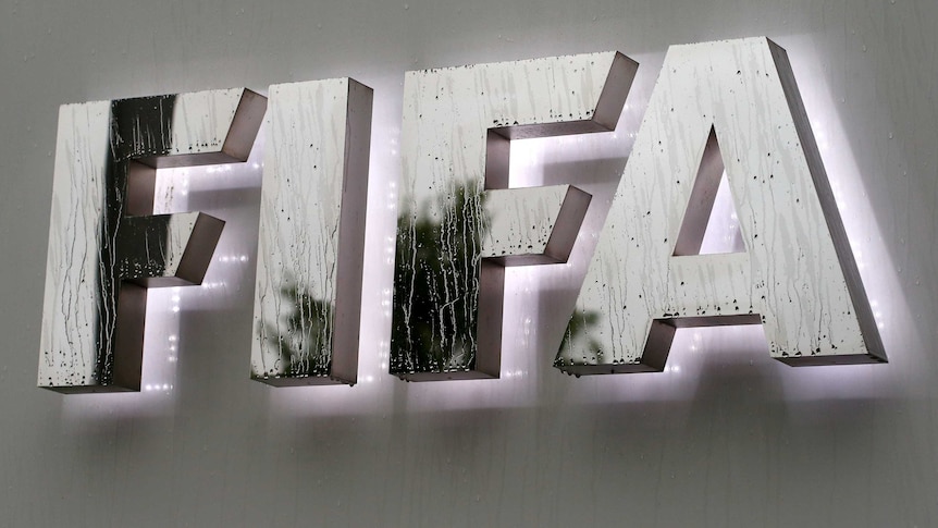 Raindrops flow down on a logo in front of FIFA's headquarters in Zurich.