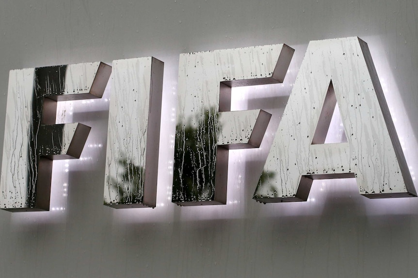 Raindrops flow down on a logo in front of FIFA's headquarters in Zurich.