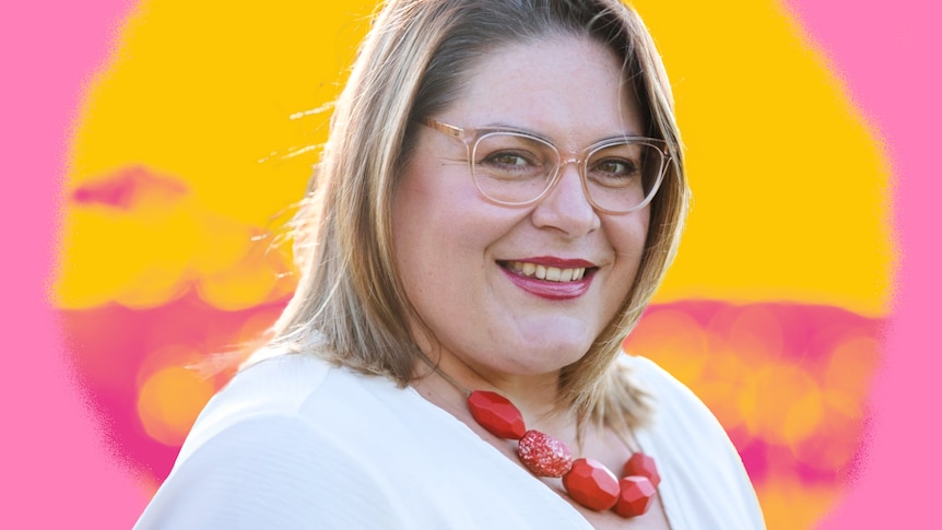 A woman wearing glasses facing almost side-on smiles at the camera, the background is an arty pink and yellow design