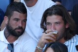Pat Carrigan drinks a beer while sitting alongside Brisbane Broncos Adam Reynolds at the Australian Open.