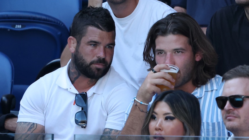 Pat Carrigan drinks a beer while sitting alongside Brisbane Broncos Adam Reynolds at the Australian Open.