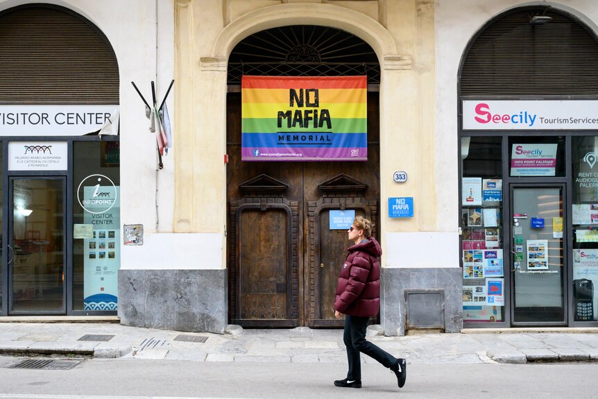 A man walks past a "no mafia" sign in Sicily
