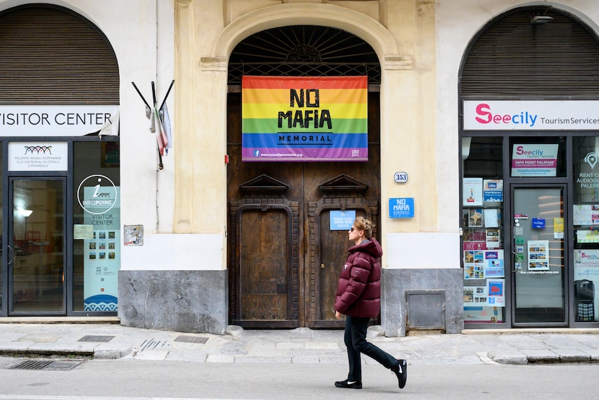 A man walks past a "no mafia" sign in Sicily