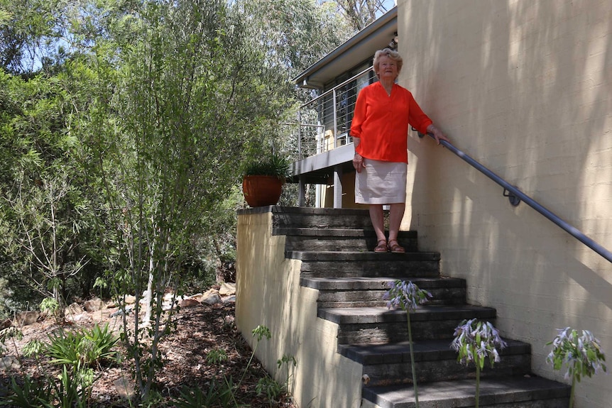 A woman stands on her front steps.