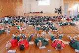 School students lie on the ground in a hall.