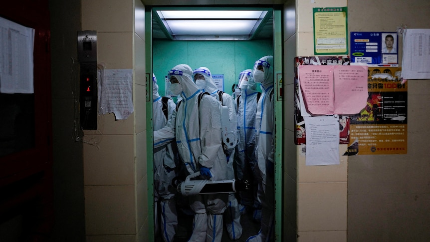 Several people in HAZMAT suits in an elevator