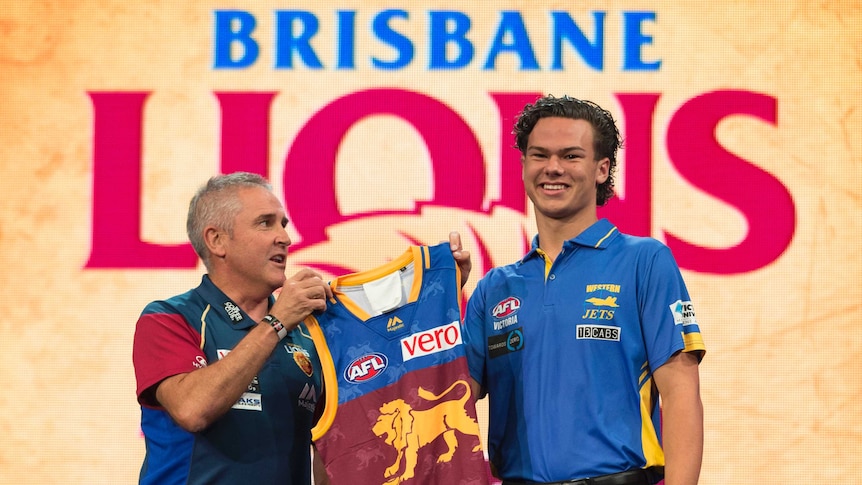 Top AFL Draft pick Cameron Rayner (R) is given his Lions guernsey by Brisbane coach Chris Fagan.