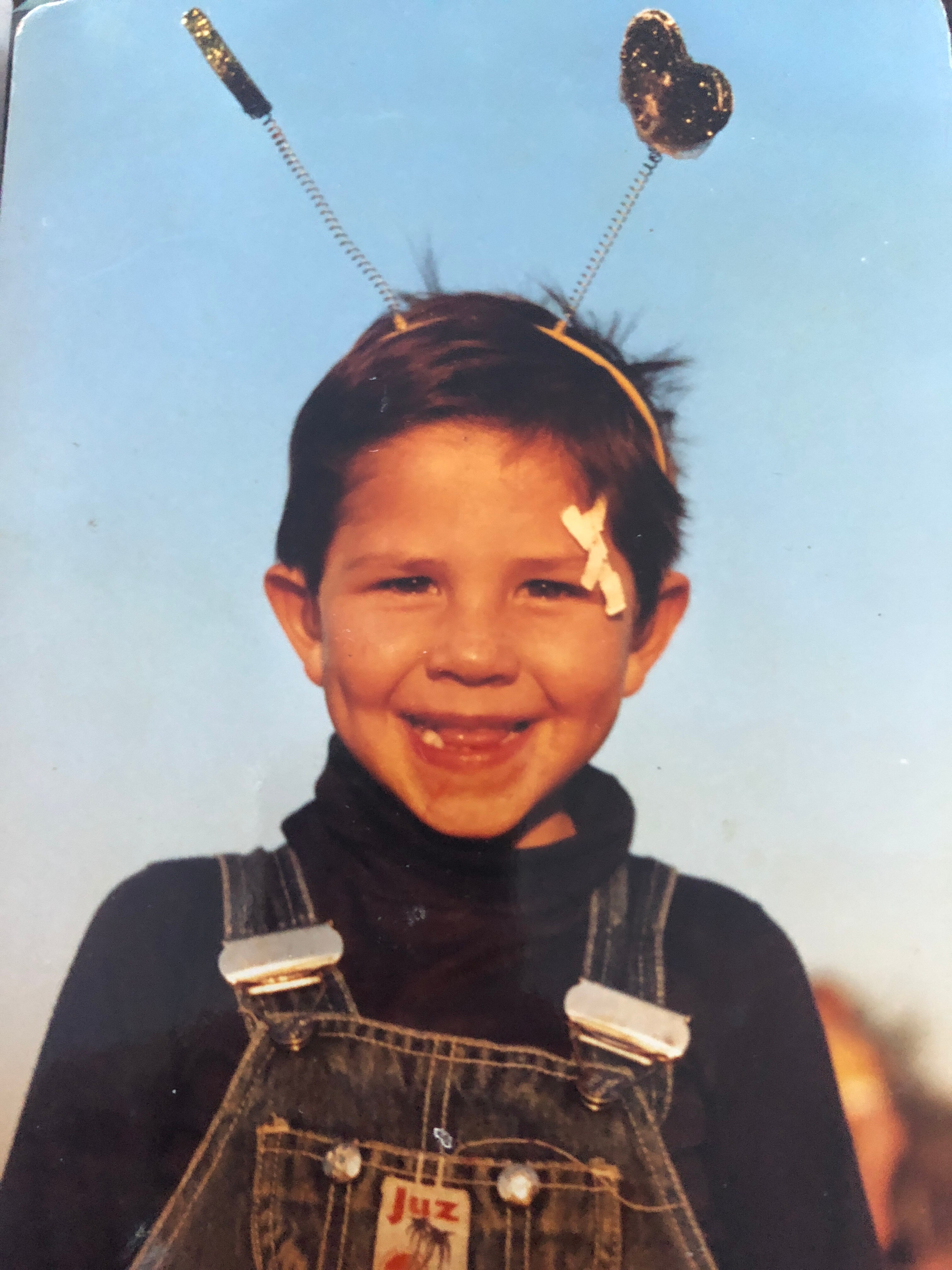 A young Daniel smiles at the camera wearing toy antennas 