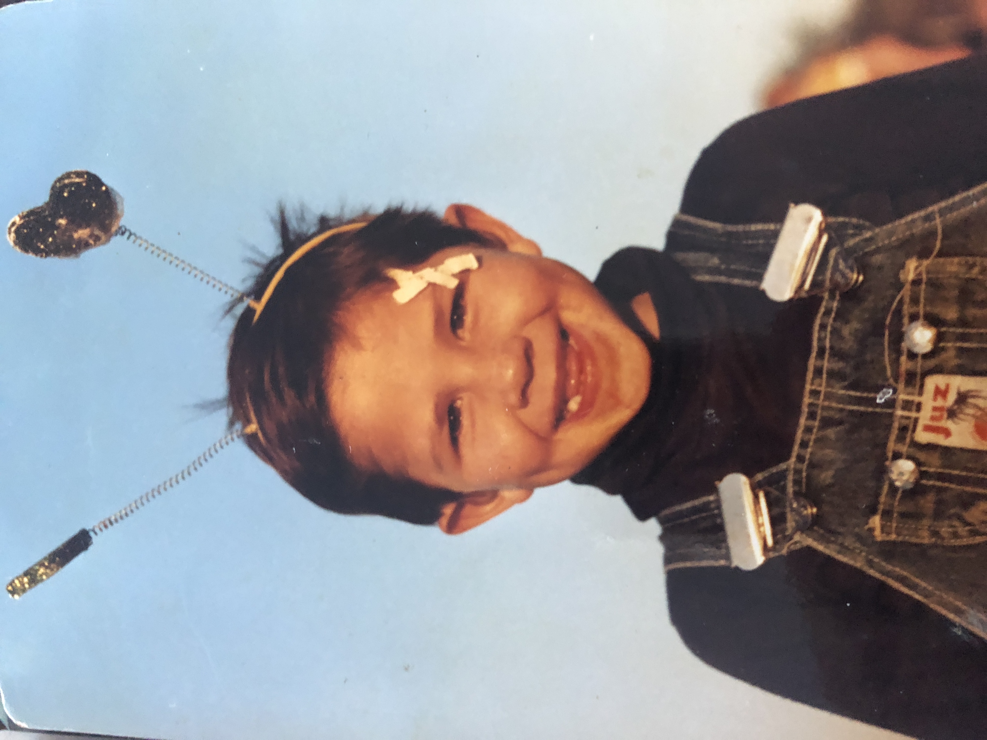 A young Daniel smiles at the camera wearing toy antennas 