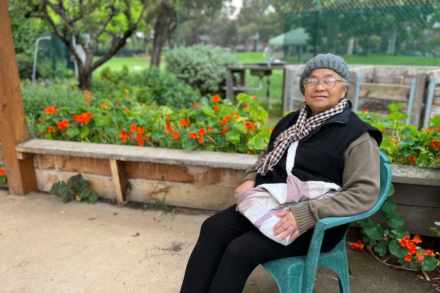 Kim Chua smiles, sitting on a chair in a covered garden area.