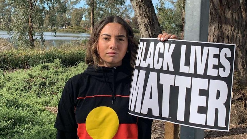 A young girl stands with a "Black Lives Matter" sign.