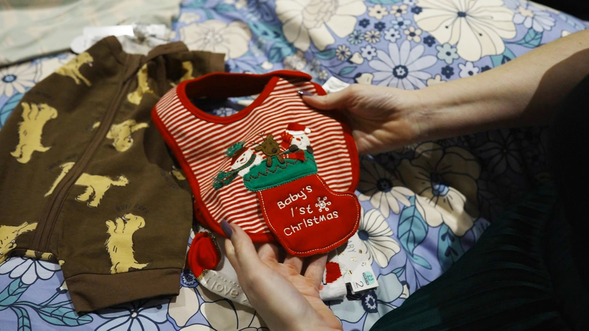 A woman holding a baby's Christmas-themed bib in her hands.