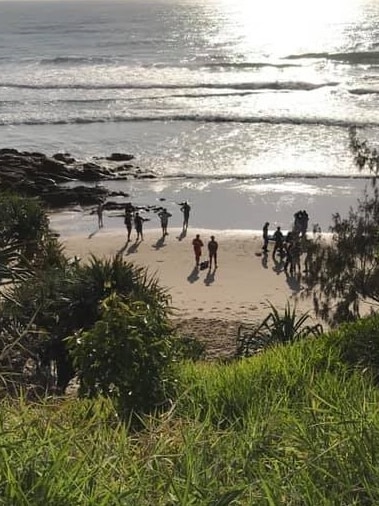 People at the scene of the drowning, looking down on the beach from dunes.