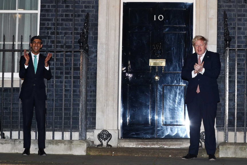 Britain's Prime Minister Boris Johnson and Chancellor of the Exchequer Rishi Sunak applaud outside 10 Downing Street.