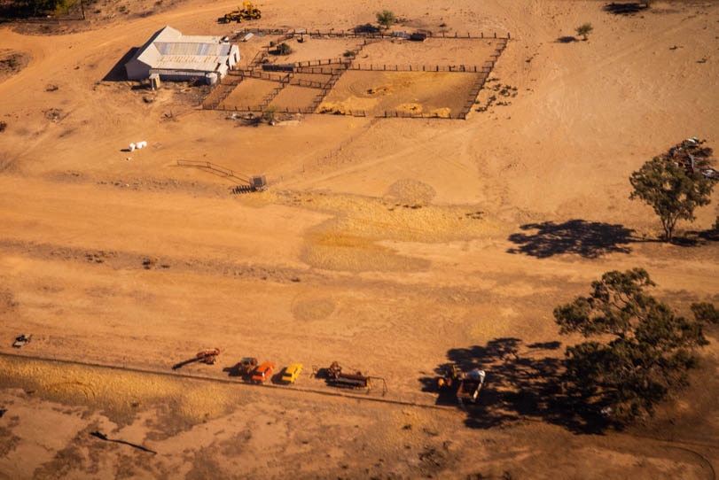 An aerial image of a parched landscape, with shearing shed and sheepyards.
