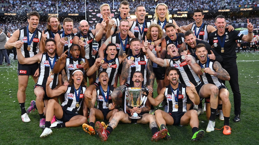 Collingwood players celebrate with the AFL premiership cup after winning the grand final.