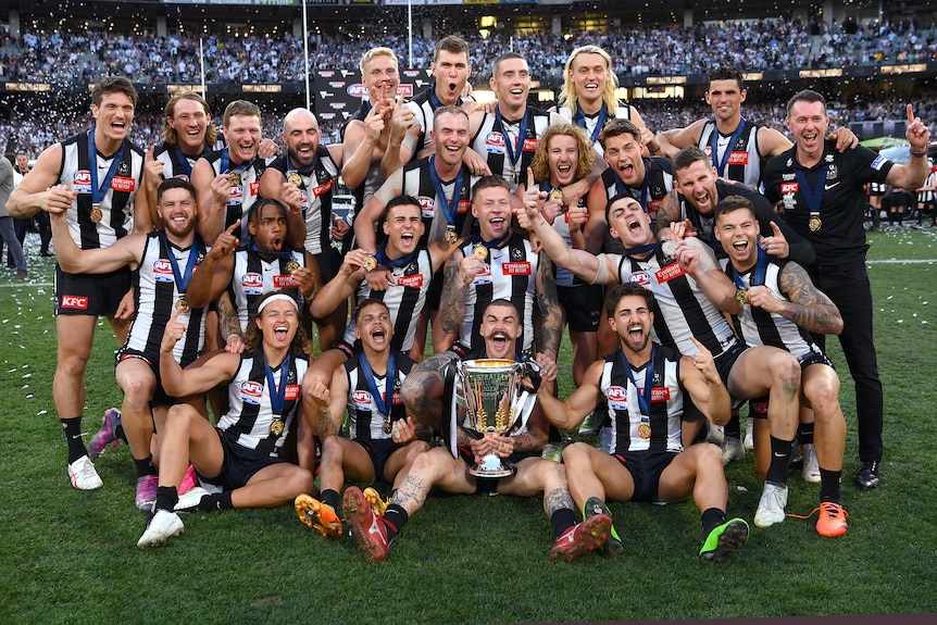 Collingwood players celebrate with the AFL premiership cup after winning the grand final.