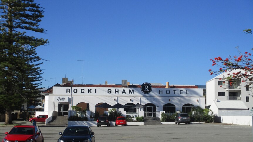 A picture of the white facade of the Rockingham Hotel including the heritage-listed pine trees and front wall