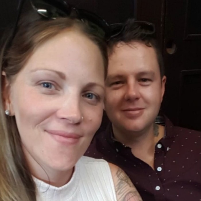 A young woman and her male partner pose for a selfie