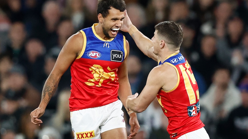 Callum Ah Chee leaps towards Dayne Zorko in celebration