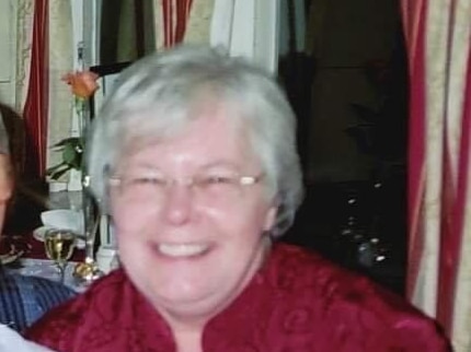 older woman with short, white hair, wearing a red top