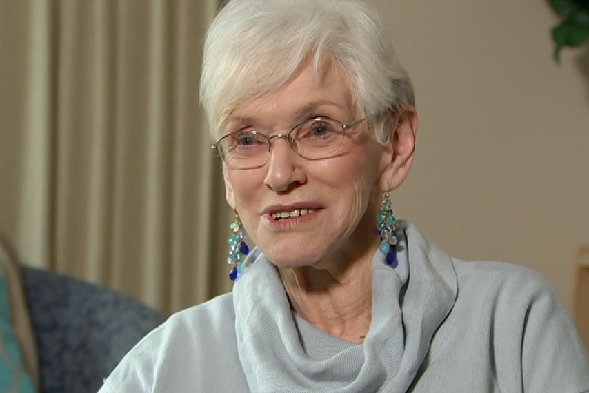 A smiling woman with short grey hair and glasses.