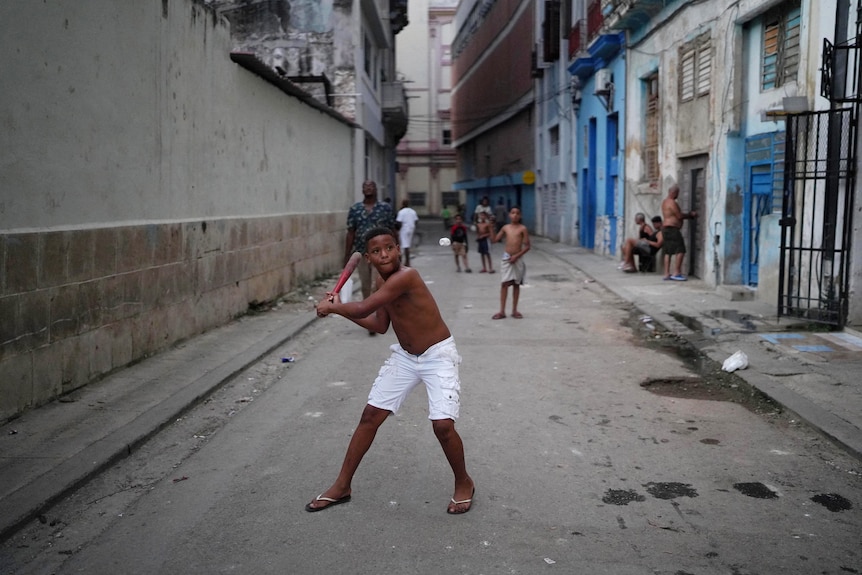 Children play baseball on the street in downtown Havana.