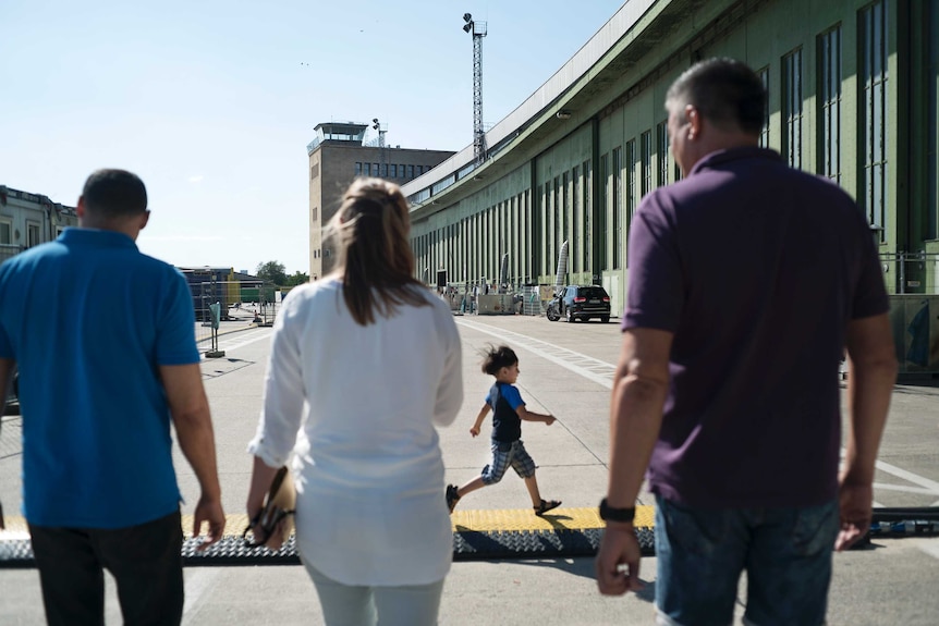 A refugee child runs past officers Najjar and Akta, and a social worker.