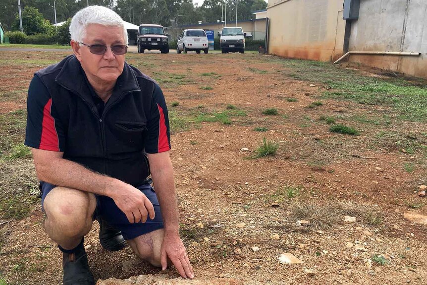 Ed Grigg crouches on the site of the former Serves You Right Cafe in Ravenshoe