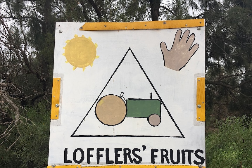 A sign with a tractor, sun and hand at the entrance to a property.