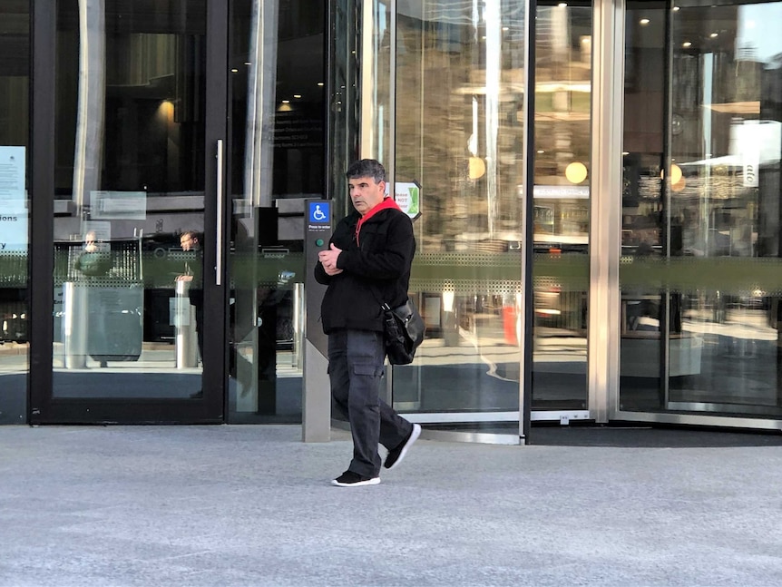 A man walks out of the doors of the ACT Magistrates Court.