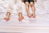 Two sets of feet in bed