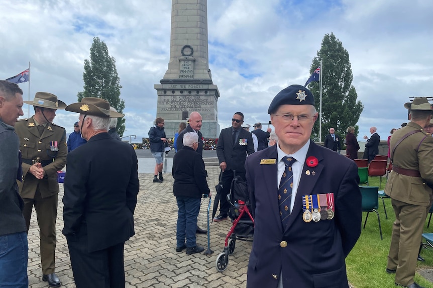 Alec looks at the camera, standing among fellow servicemen and women at the Cenotaph in Hobart.