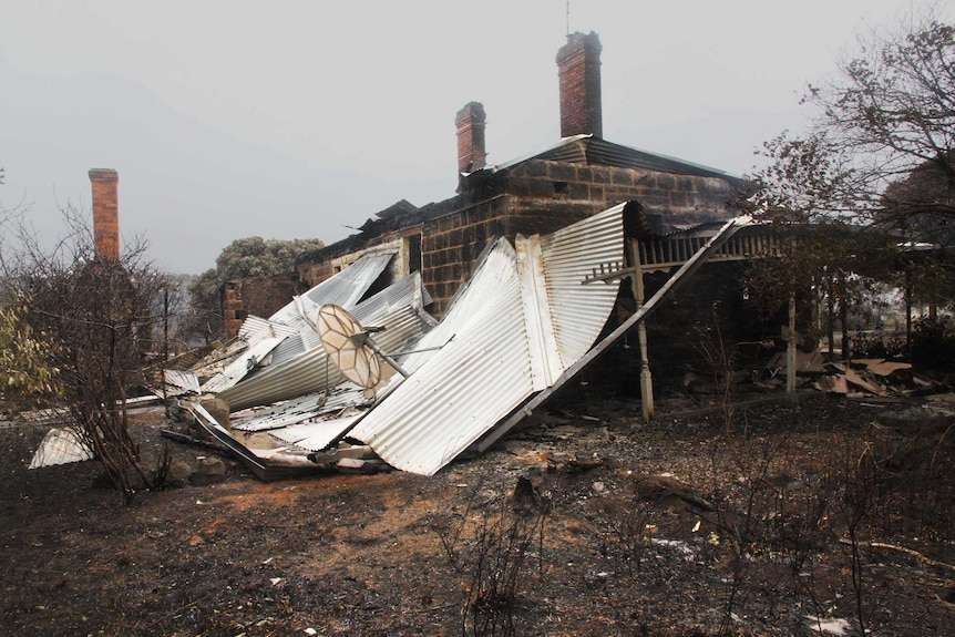 A pile of tin next to a burnt-out house destroyed by bushfires.